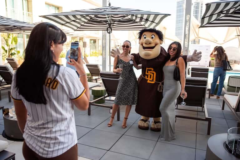 Rooftop terrace with mascot character posing with guests under striped umbrellas