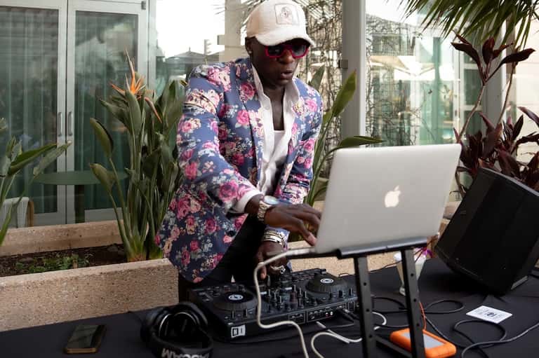 Man in floral blazer working on laptop outdoors surrounded by tropical plants