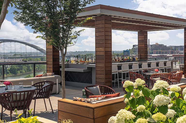 Rooftop bar and lounge area with panoramic city views, white flowers, and modern outdoor seating