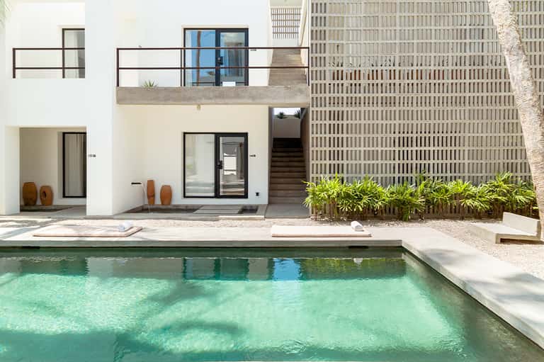Modern poolside villa with white exterior, turquoise water, and minimalist architectural design
