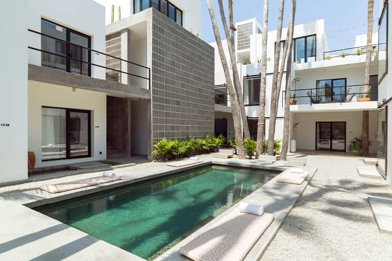 Modern white courtyard home with pool, palm trees, and clean architectural lines in minimalist design