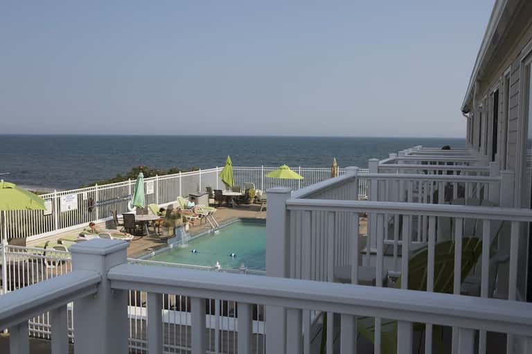 Ocean-view deck with small pool, lounge chairs, white railings, and calm sea horizon in background