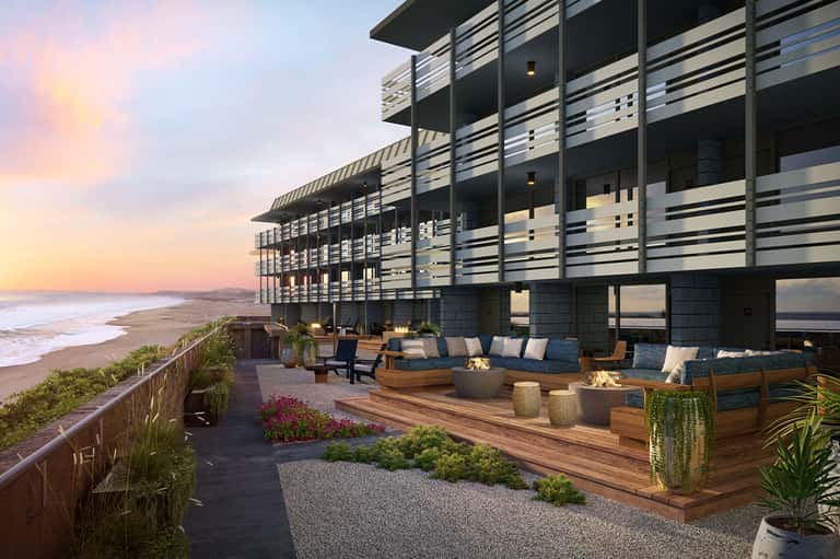 Modern beachfront resort at dusk with slatted railings, firepit seating, and ocean views