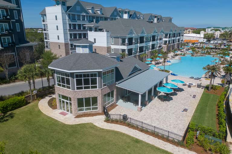 Coastal resort complex with pool, beach umbrellas, and residential-style buildings