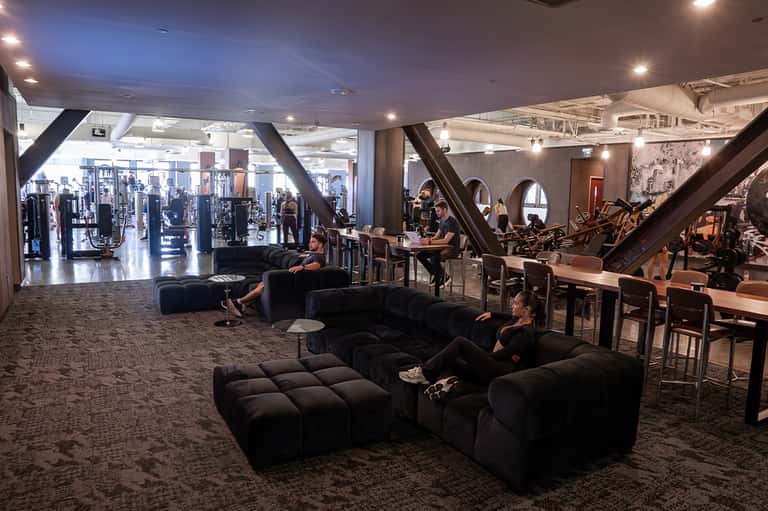 Modern hotel fitness center with gym equipment and seating area with large windows