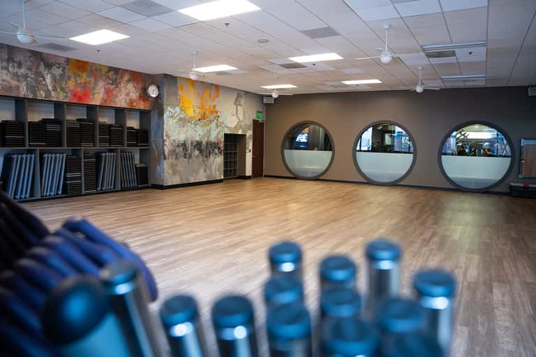Fitness studio with wooden flooring, circular mirrors, and colorful wall art
