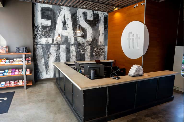 Casual spa retail counter with large weathered FAST signage, wooden accent wall, and product shelves