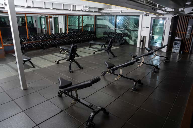 Modern fitness center with exercise bikes, benches, and dumbbells along glass windows
