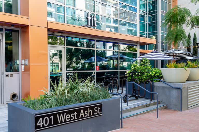 Urban street-level cafe entrance with striped umbrellas and modern building facade