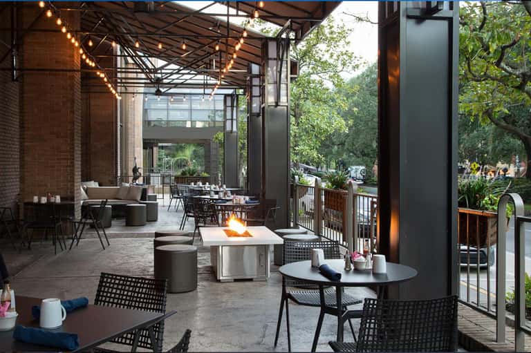 Contemporary outdoor patio with firepit, lounge seating, string lights, and green landscape views
