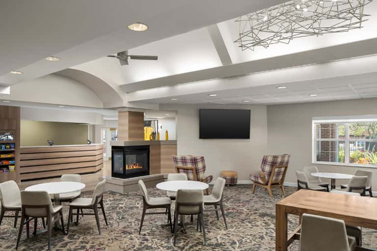 Modern hotel lobby lounge with fireplace, skylight, seating areas, reception desk, and contemporary decor