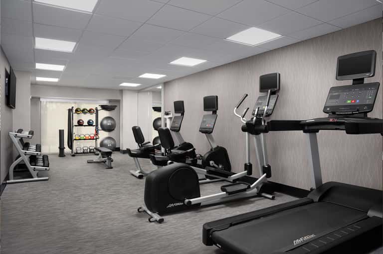 Modern fitness center with cardio equipment, exercise bikes, weight rack, and mirrors