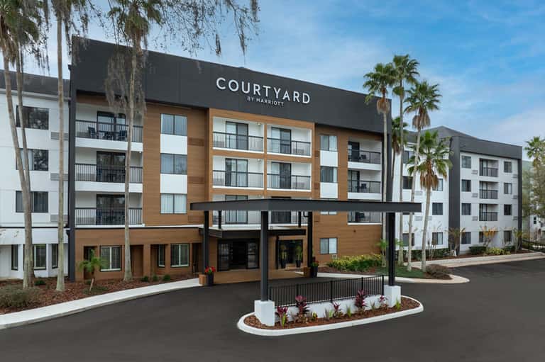 Courtyard by Marriott exterior featuring wood and metal facade, palm trees, and modern architecture