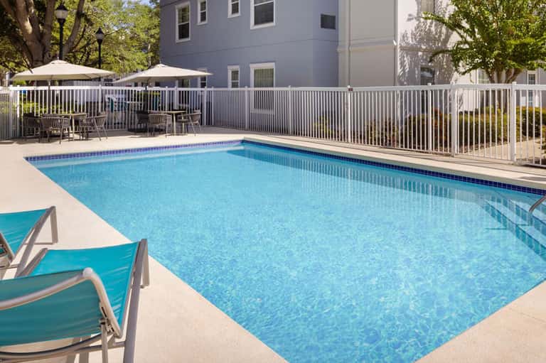 Resort outdoor swimming pool with white safety railing and lounge chairs