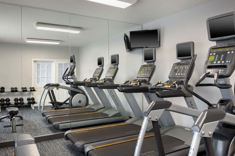 Fitness center with treadmills, exercise bikes, and wall-mounted monitors
