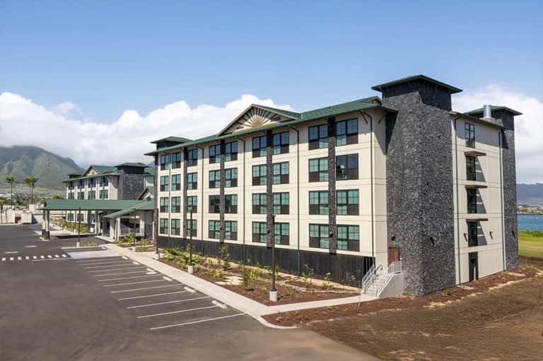 Multi-story residential hotel building with cream and stone exterior near ocean
