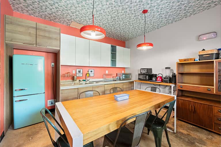 Retro-style kitchen with turquoise refrigerator, coral accents, and geometric ceiling pattern