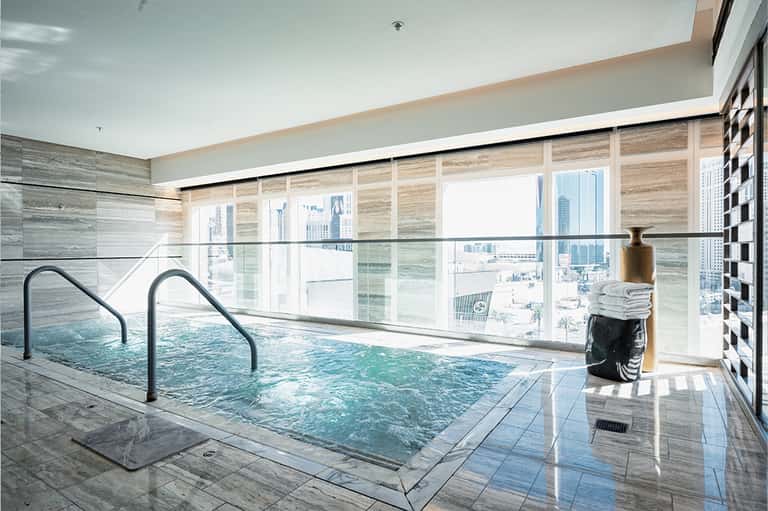Indoor swimming pool with floor-to-ceiling windows overlooking city skyline