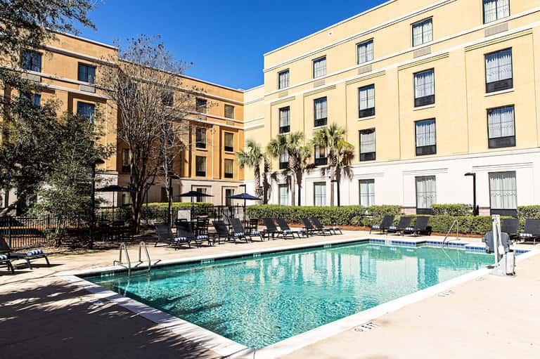 Resort courtyard pool surrounded by yellow and white historic building architecture with palm trees