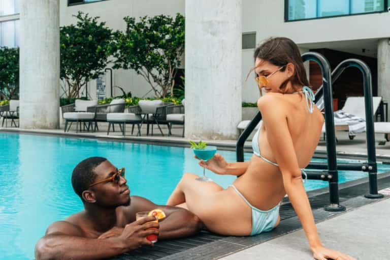 Guests enjoying poolside cocktails at modern resort with geometric architecture and water features