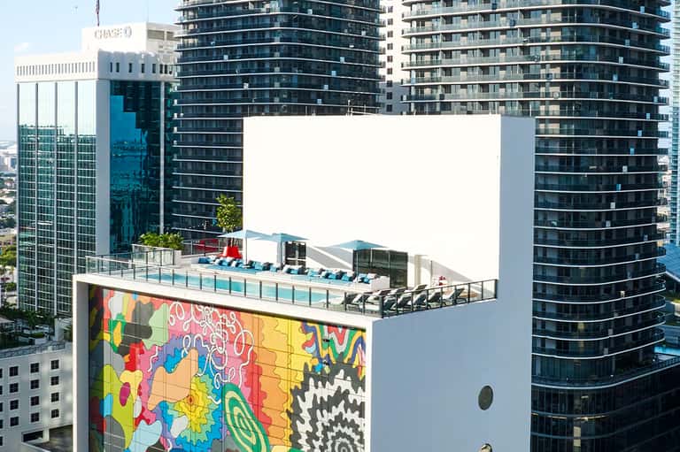 Rooftop pool deck with colorful mural art and lounge chairs overlooking city skyline