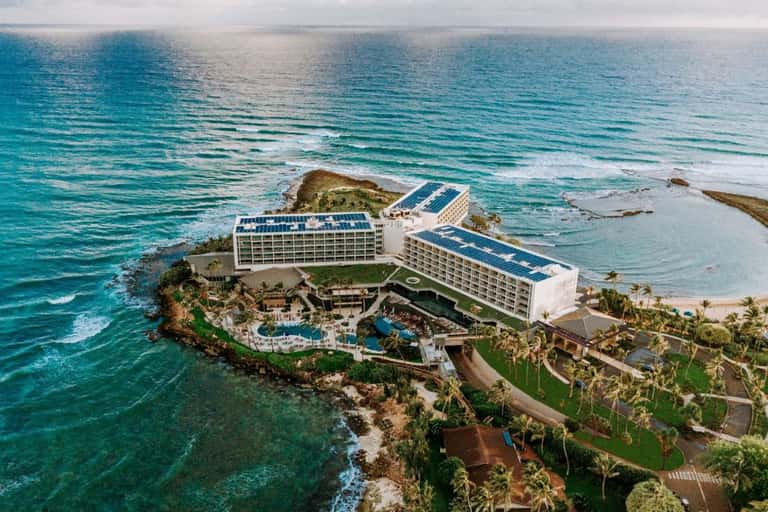 Aerial view of coastal resort hotel built on rocky peninsula surrounded by turquoise ocean