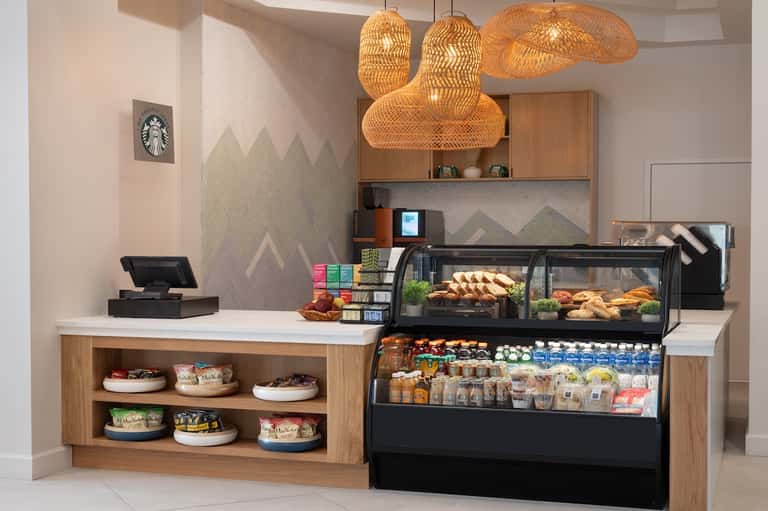 Starbucks café counter with woven pendant lights, pastry display case, and mountain-themed wall art