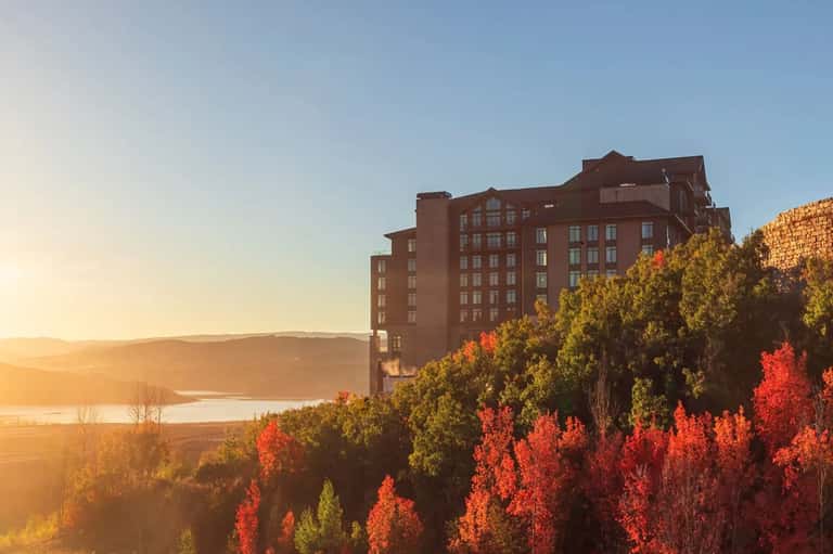 Red brick hotel building at sunset with autumn foliage and lake backdrop