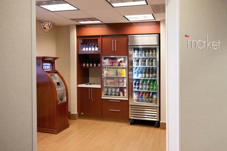 Hotel market convenience shop with ATM, beverage cooler, vending machine, and wooden cabinetry