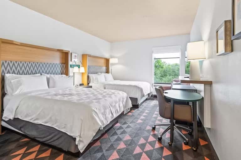 Modern hotel bedroom with two queen beds, geometric patterned headboards, and work desk