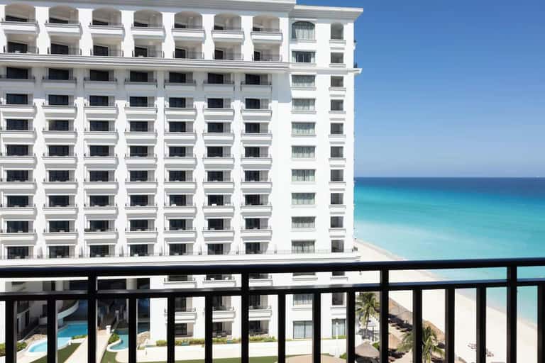 White multi-story beachfront hotel building with ocean and sand beach visible