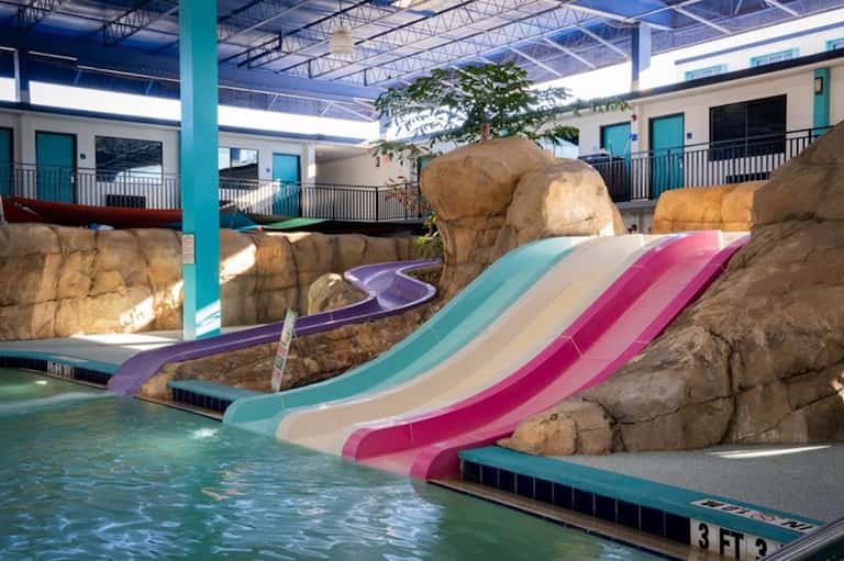 Indoor water park with colorful slides, rock formations, and shallow pool