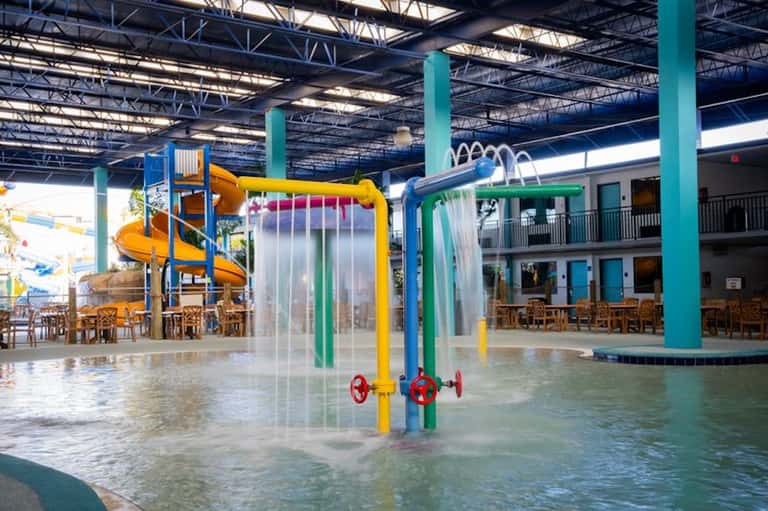 Indoor water park with colorful water slides, splash pad, and supervised play area