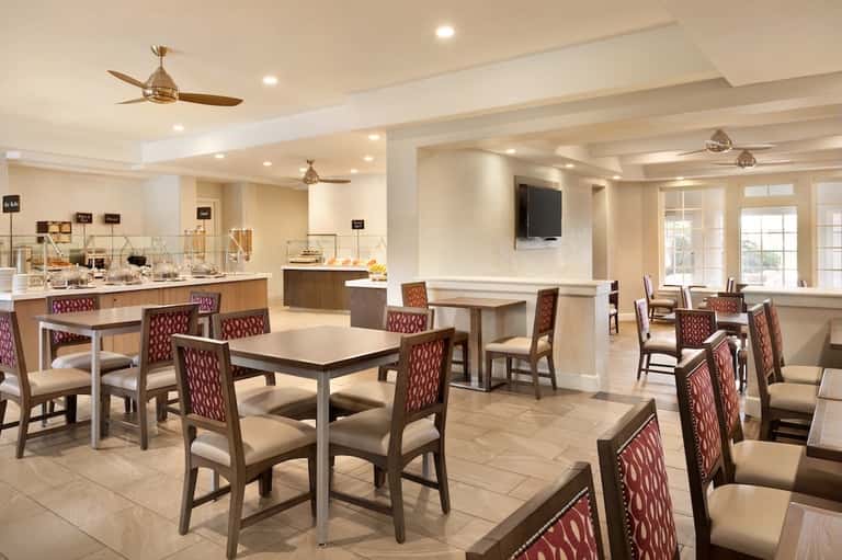 Casual dining area with multiple tables, burgundy chairs, buffet station, and flat-screen TV