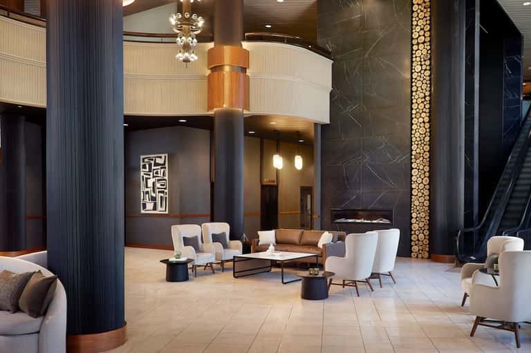 Luxury lobby with marble flooring, modern furniture, soaring columns, and fireplace accent