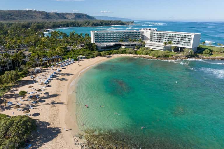Resort hotel on Hawaiian beach with turquoise waters, sandy shore, and mountain backdrop