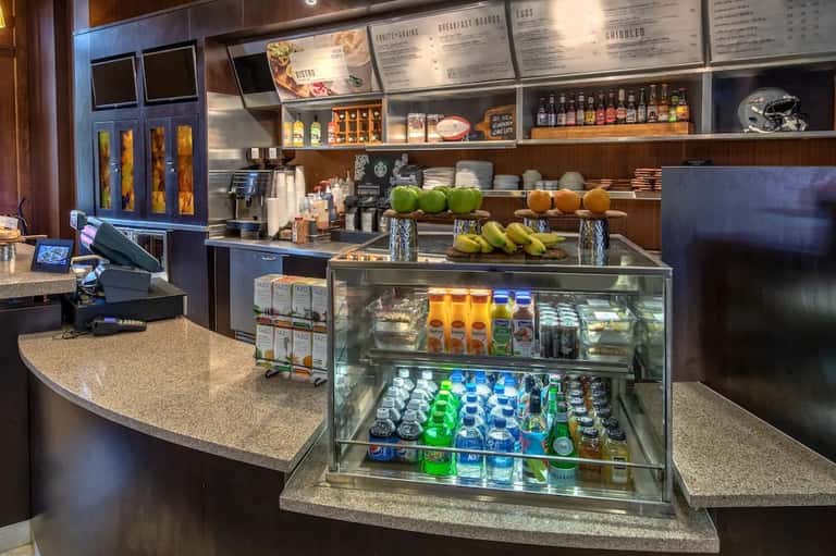 Modern hotel café counter with beverage coolers, breakfast menu, and menu boards