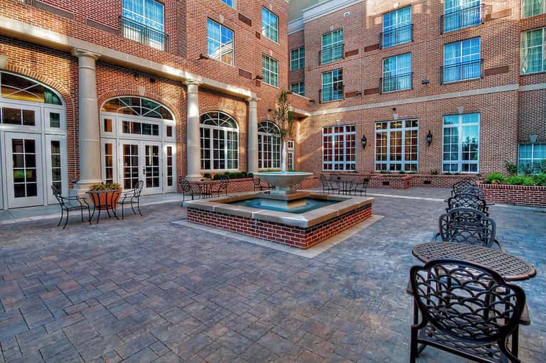 Brick courtyard with decorative fountain, seating areas, and arched architectural details