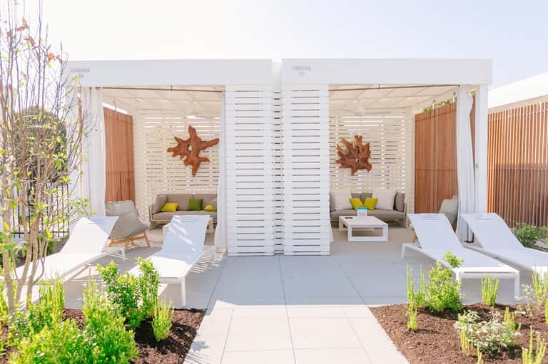 Luxury cabana with white louvered doors, seating areas, and decorative starfish accents