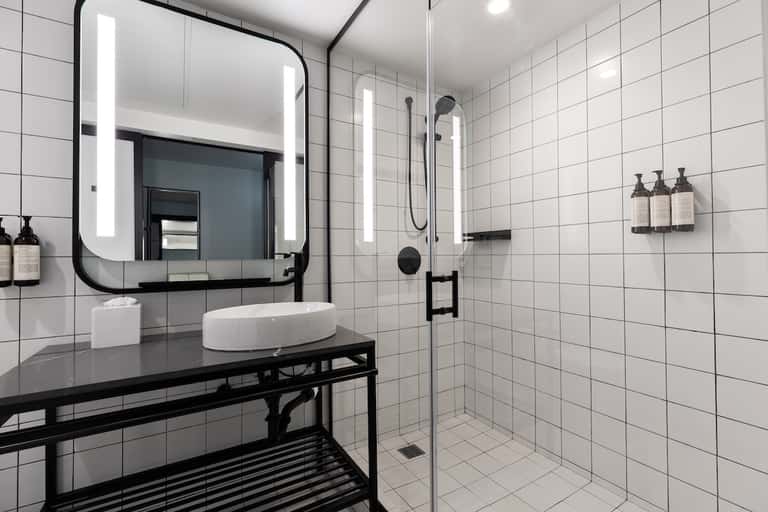 Contemporary bathroom with white subway tiles, black vanity, and illuminated mirror