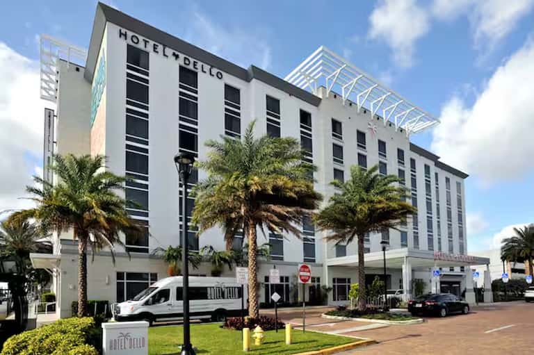 Hotel Dello white building with palm trees, modern architecture, and ground-level entrance