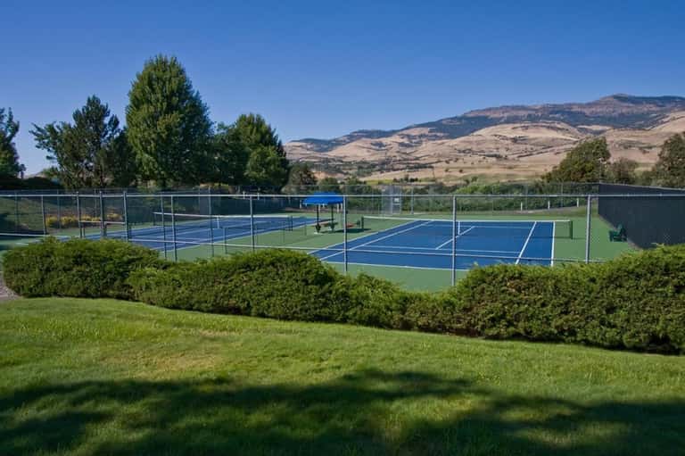 Tennis courts with blue playing surfaces set against rolling hills landscape