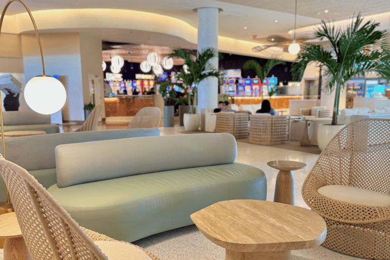 Modern hotel lobby lounge with curved sofa, pendant lighting, potted plants, and contemporary furnishings