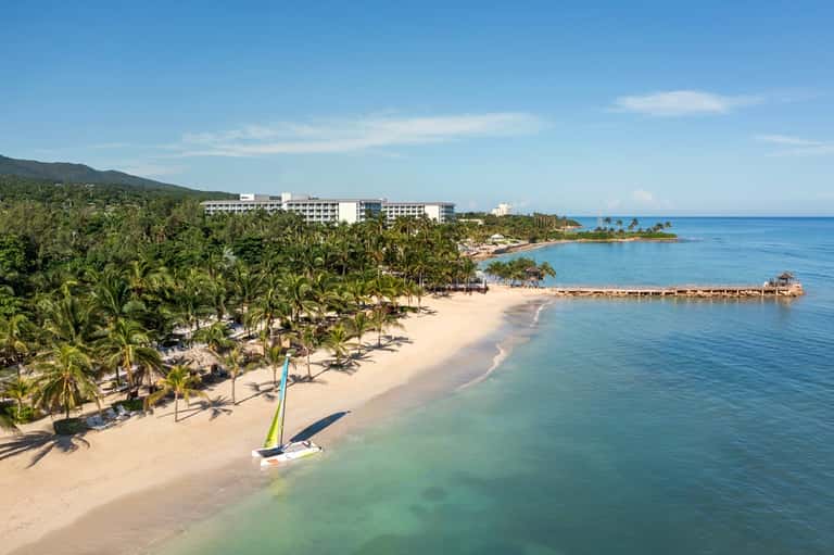 Beachfront resort on tropical island with white buildings and pristine sandy beach