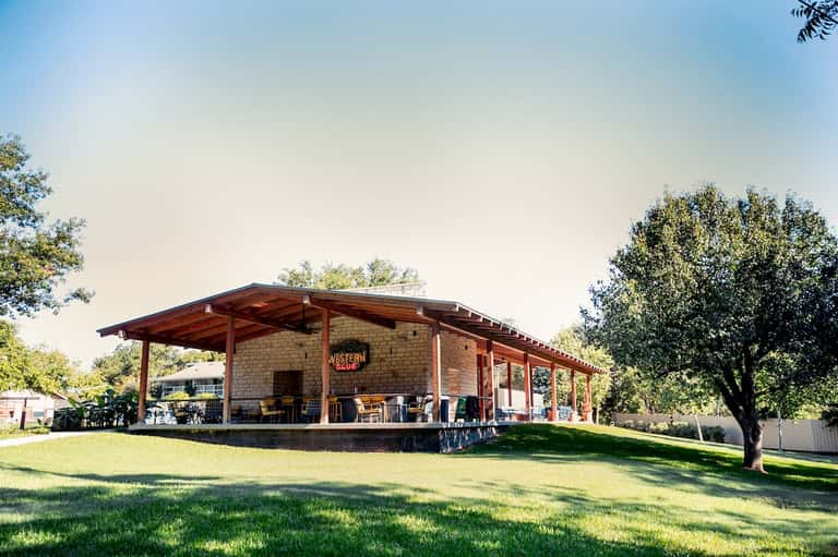 Western-style lodge building with covered porch and metal roof set on manicured grounds