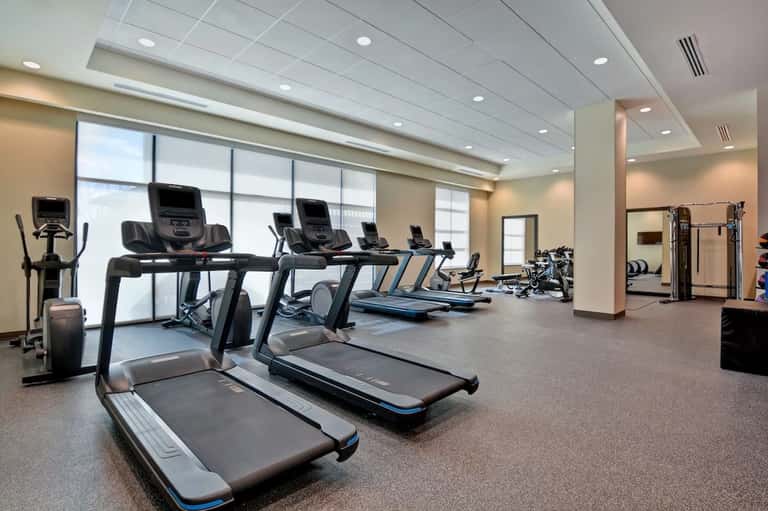 Hotel fitness center with treadmills and exercise equipment by large windows