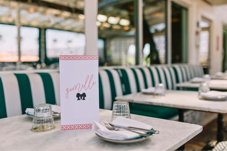 Elegant dining table setting with striped green and white chairs and water view