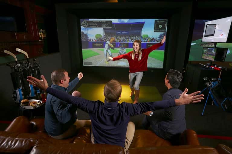 Group playing interactive sports video game on large screen in modern entertainment lounge