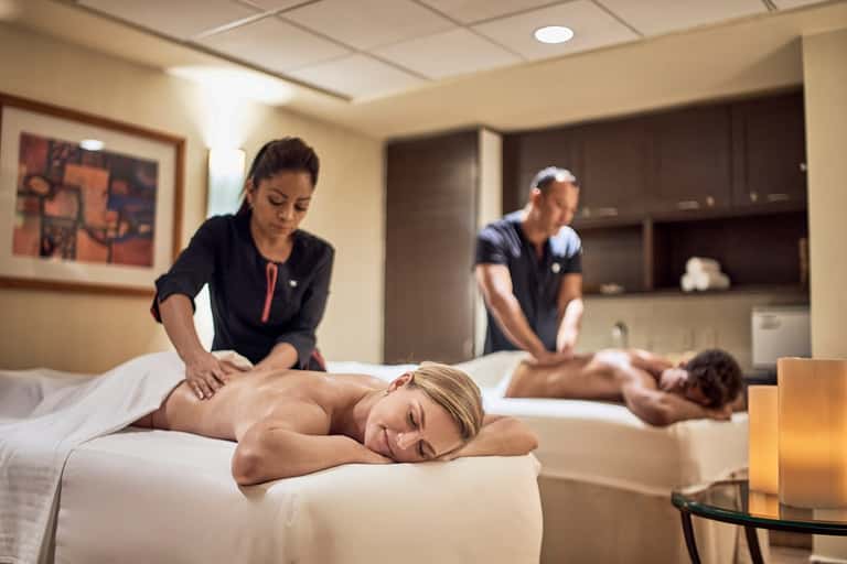 Spa treatment room with therapist providing massage to client on white table