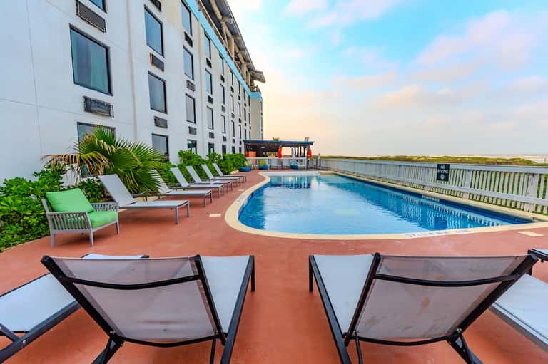 Resort pool with colorful lounge chairs and waterfront views at sunset